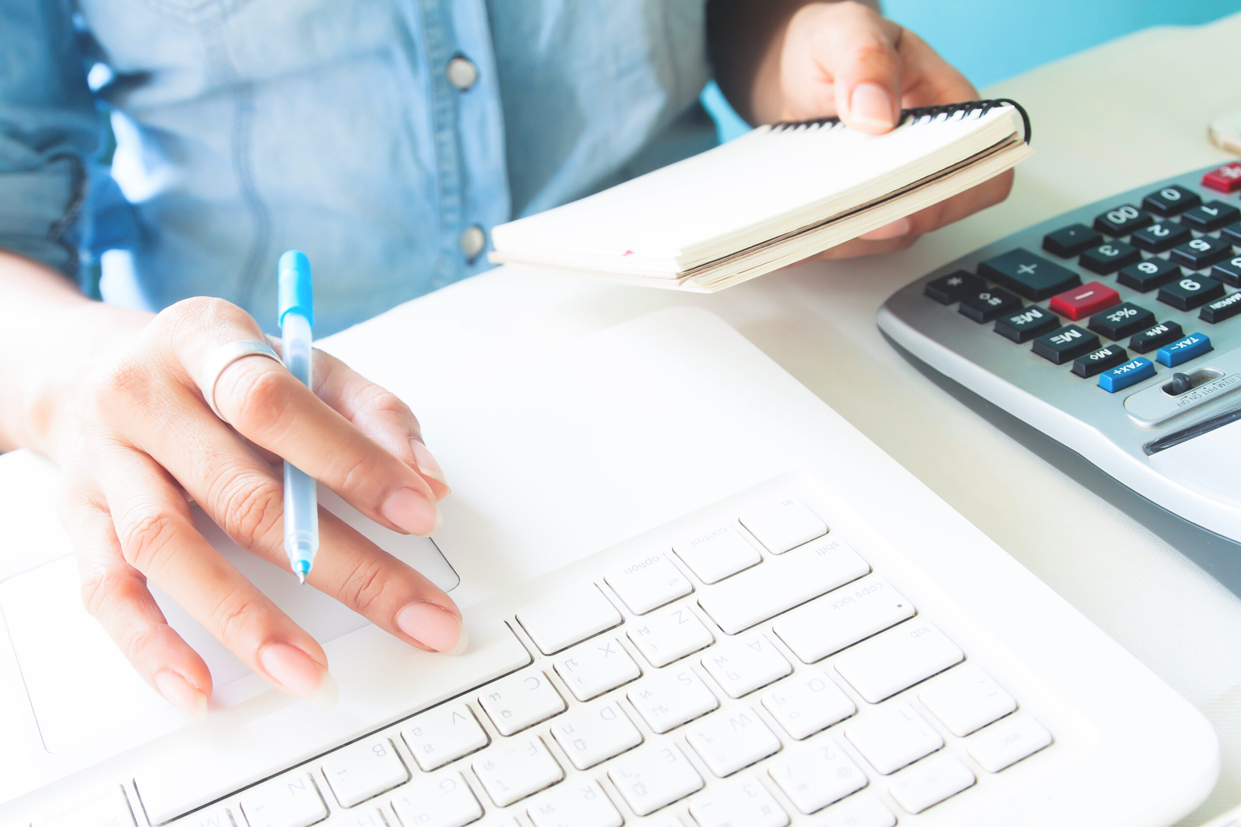accountant working on laptop with a notepad and calculator