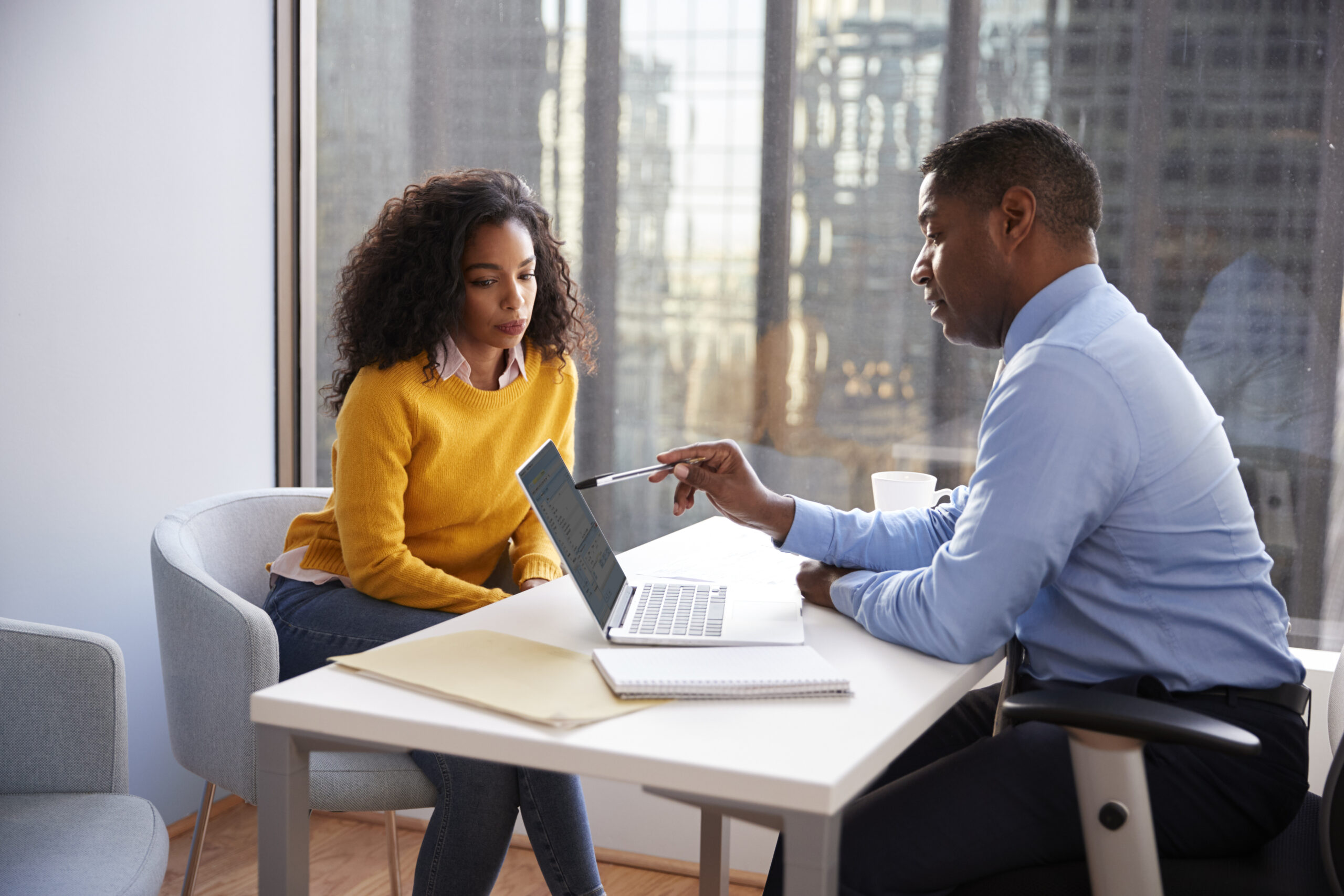 accountant sitting with customer discussing finances over laptop